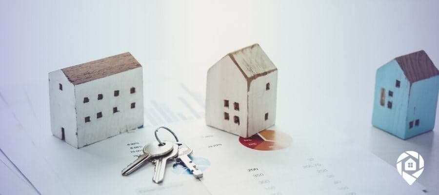 Real estate wholesaling concept with house models, keys, and market charts.